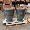 Image of Two large blue anduze urns on a pallet in an industrial setting with boxes and shelves in the background.