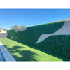 Image of An image of a backyard with a wave shaped Artificial Flowering Buxus Hedge Plant Panels installed on a light block wall, green turf, a pool edge, and palm trees under a sunny sky