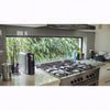 Image of Modern kitchen with gas stove and coffee machine, featuring a window view of greenery wall on fence outside.
