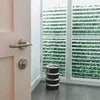 Image of A room corner featuring white plantation shutters. The partially open slats look out onto the Artificial Ivy Leaf Hedge 1m x 1m Plant Wall Screening Panel UV Protected installed on a wall outdoors