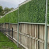 Image of A long wooden fence upgraded with a gray frame, Artificial Jasmine Hedge Plant Wall Screen Panels, and matching lattice in a residential backyard with a small black gate