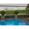 Image of A landscaped pool area on a rainy day, featuring dark tiled decking and a layered privacy fence with topiary trees, wooden panels, lattice, and Artificial Jasmine Hedge Plant Wall Screen Panels