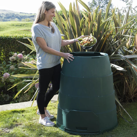 Person disposing of food waste into a Green Johanna compost bin in a garden setting