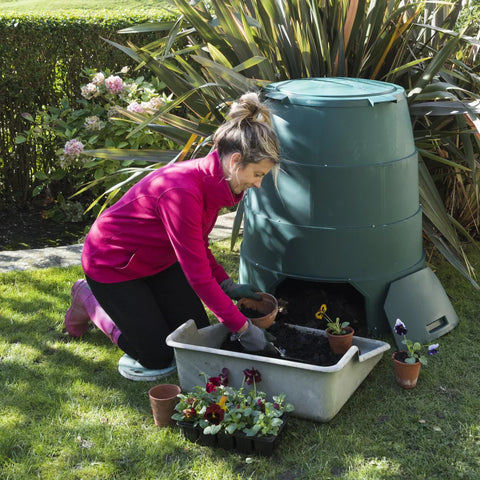 Person gardening with a Green Johanna compost bin in a garden setting