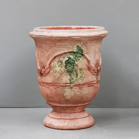 Terracotta urn with decorative elements on a gray background