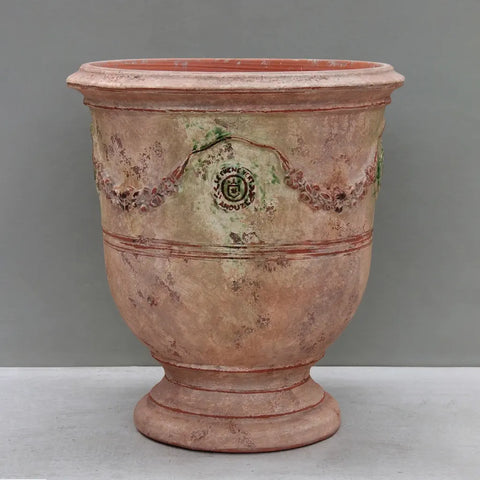 Terracotta urn with decorative patterns on a gray background