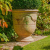 Image of Decorative garden urn on a stone path with greenery