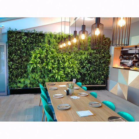 Dining area with a wooden table, green chairs, and a living plant wall.
