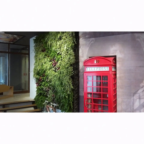 Red telephone box next to a living wall in an indoor setting