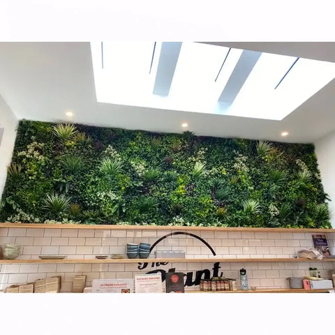 Artificial green living wall in a modern interior setting with shelves below