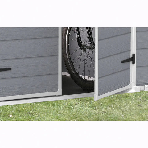 Gray outdoor storage shed with a bicycle inside, on a grassy background