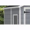 Image of Gray storage shed with a white door and black handle, surrounded by greenery.