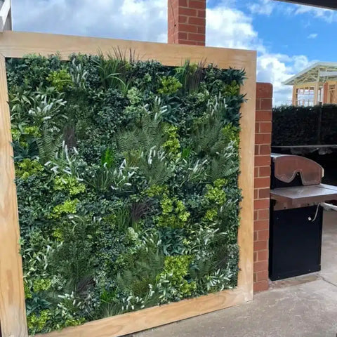 Artificial Vertical Garden of Eden Installed on a patio area with a timber frame surrounding it and a barbeque visible in the background