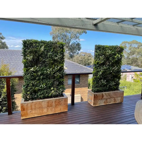 two Artificial Vertical Garden of Eden walls sitting in wooden planter boxes on a balcony
