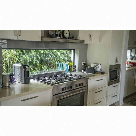 Modern kitchen with stainless steel appliances and a window view of greenery.
