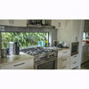 Image of Modern kitchen with stainless steel appliances and a window view of greenery.