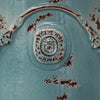 Image of Close-up of a blue ceramic plate with a logo and text, showing signs of wear.