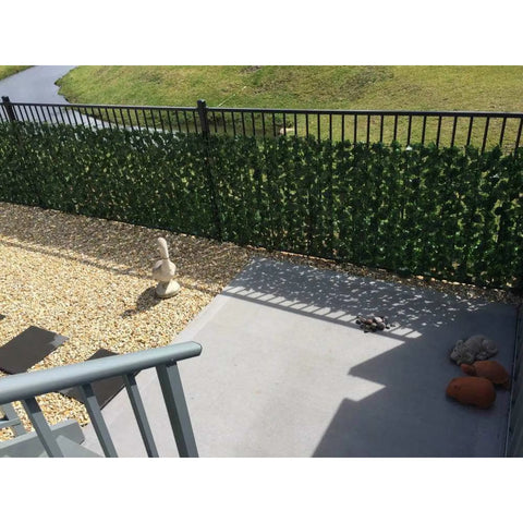 Double Sided Artificial Ivy Roll 3m x 1m Screen installed on an outdoor railing beside a stone-paved walkway near the staircase