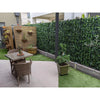 Image of A private courtyard featuring the Artificial Ivy Leaf Hedge Panels, wooden slat screen with hanging planters, tiled patio with dining set, potted plants, and a mix of tiles and artificial turf