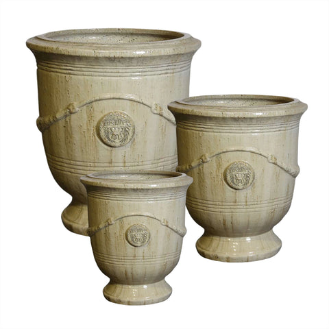 Three sand beige ceramic french urns with decorative elements on a white background