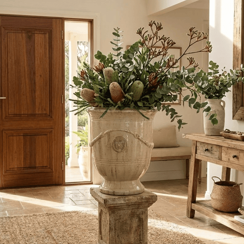 sand glazed french urn in entryway on a pillar with a floral arrangement
